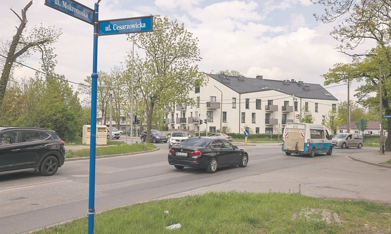 Skrzyżowanie ulic Awicenny, Wiejskiej i Mokronoskiej, widziane z perspektywy ulic Mokronoskiej i Cesarzowickiej. Jadące samochody, biały budynek mieszkalny w tleod
