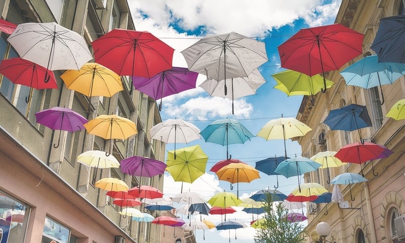 Kolorowe parasolki zawieszone nad ulicą w mieście na tle nieba