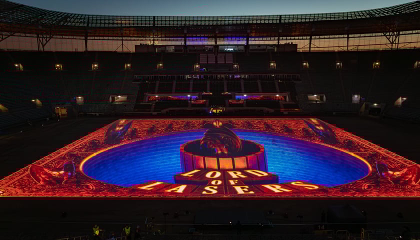 Kolorowe iluminacje na płycie stadiony z napisem "Lord of Lasers"