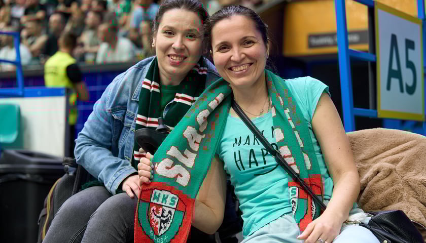 Dwie uśmiechnięte dziewczyny kibicują koszykarskiemu Śląskowi podczas meczu