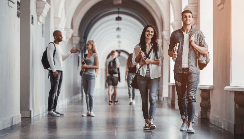 Studentki i studenci idący po korytarzu. Zdjęcie ilustracyjne