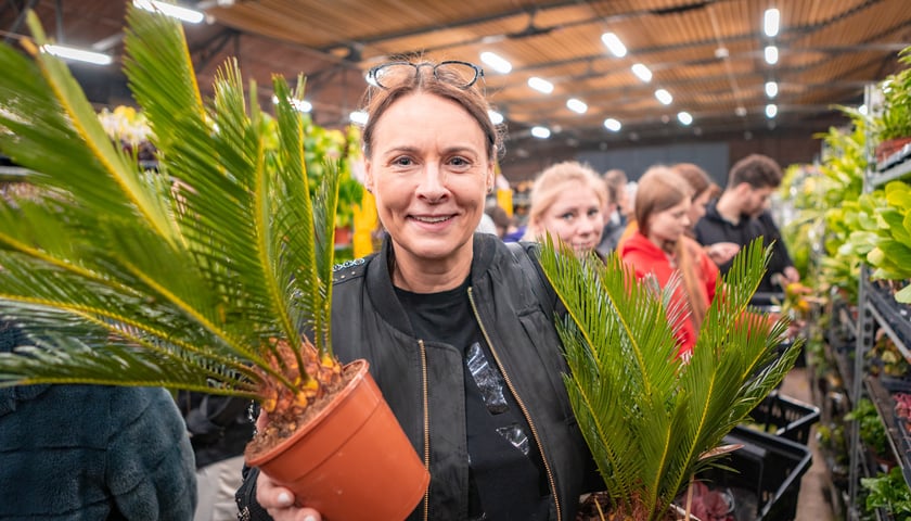 Festiwal Roślin w Czasoprzestrzeni we Wrocławiu. Na zdjęciu uśmiechnięta kobieta z kwiatem doniczkowym