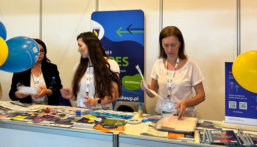Trzy kobiety na stoisku Dolnośląskiego Wojewódzkiego Urzędu Pracy podczas poprzedniej edycji targów