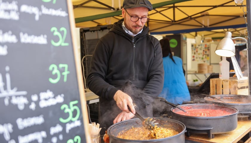 Festiwal Smaków na placu Wolności we Wrocławiu. Na zdjęciu mężczyzna przyrządza jedzenie w wielkiej patelni