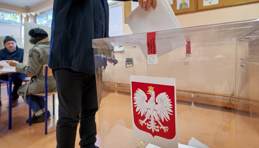 Na zdjęciu mężczyzna wrzucający kartę do urny wyborczej.