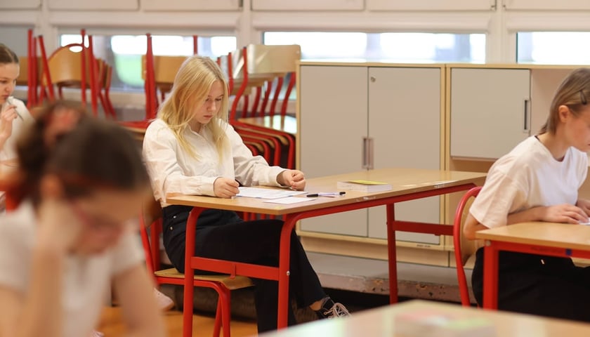 Ósmoklasiści piszący egzamin z j. polskiego, zdjęcie ilustracyjne