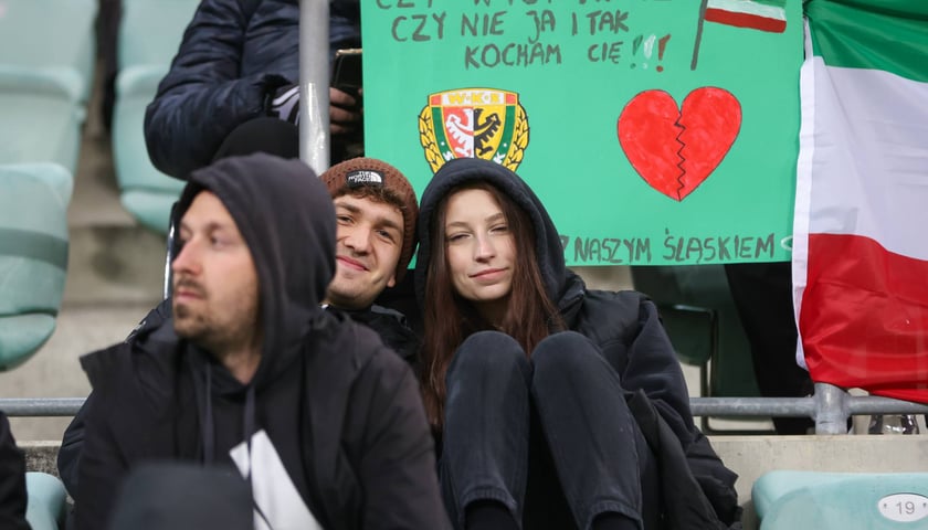Kibice z transparentem, na którym napisano: "czy wygrywasz, czy nie, ja i tak kocham cię"