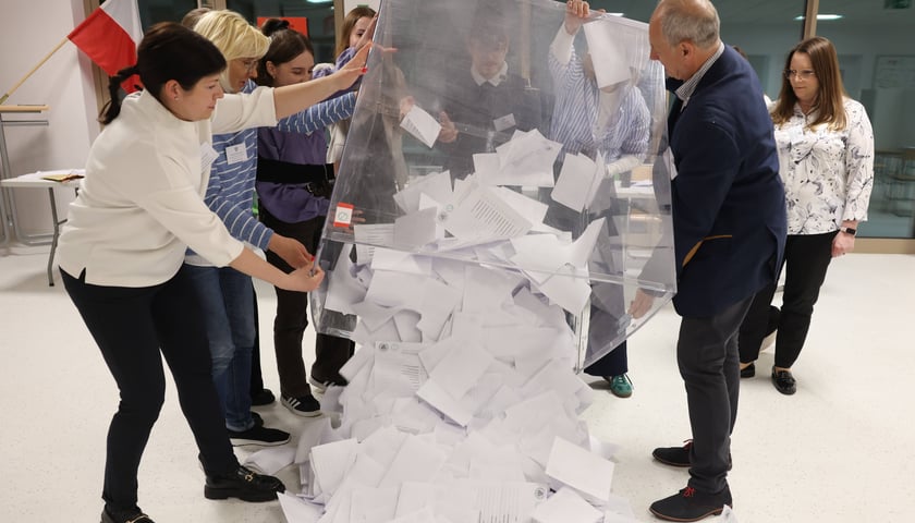 Opróżnianie urny wyborczej po I turze głosowania w obwodowej komisji wyborczej przy ul. Asfaltowej we Wrocławiu. Na zdjęciu kilka osób wysypuje karty do głosowania z plastikowego pojemnika
