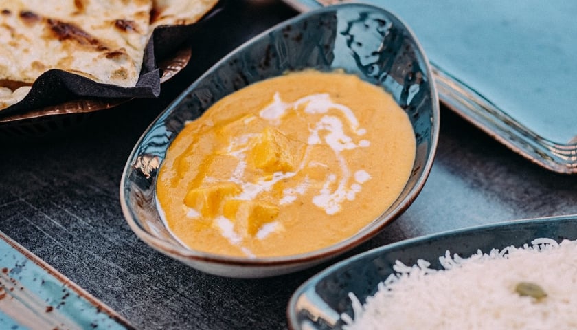 W India Concept zjemy pokazane na zdjęciu curry z ryżem i placuszkami naan.