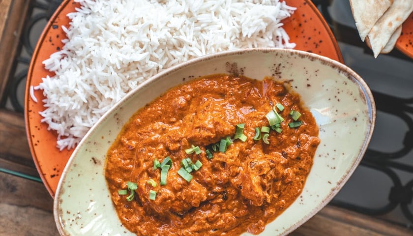 Na zdjęciu miska z ryżem, obok niej talerz z daniem kuchni indyjskiej z wrocławskiej restauracji THALI.