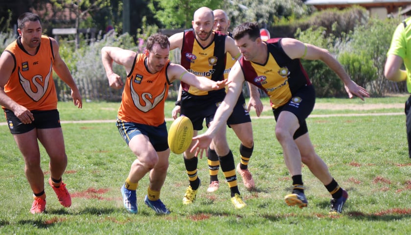 Kilku zawodników walczy o jajowatą piłkę w czasie meczu futbolu australijskiego.