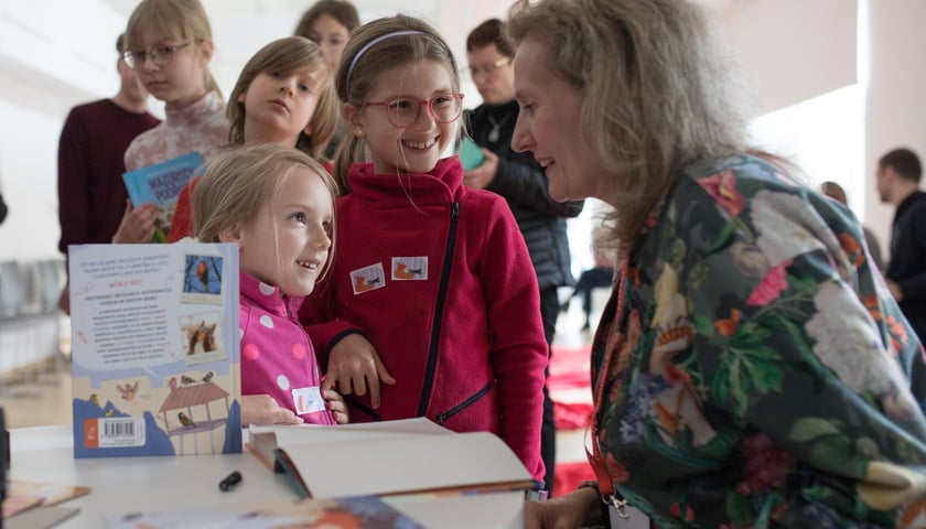 Zdjęcie ilustracyjne: jedna z poprzednich edycji Międzypokoleniowego Festiwalu Literatury Dziecięcej Ojce i Dziatki. Na zdjęciu dzieci rozmawiające z uśmiechniętą kobietą.
