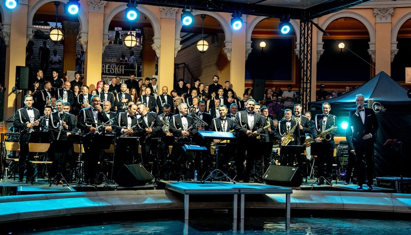 Muzycy z orkiestry dętej i dyrygent wieczorową porą na Bastionie Sakwowym