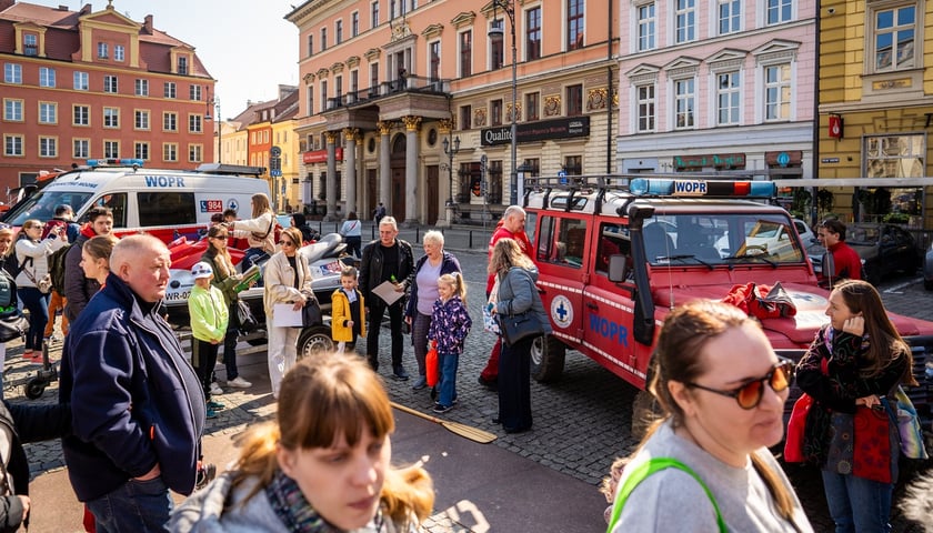 Dwa wozy Wodnego Ochotniczego Pogotowia Ratunkowego ustawione na pl. Solnym i ludzie, którzy je oglądają