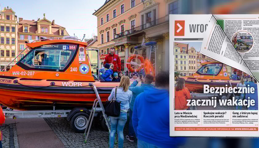 Pomarańczowa motorówka WOPR na pl. Solnym zwiedzana przez dzieci pod opieką ratownika w czerwonym polarze