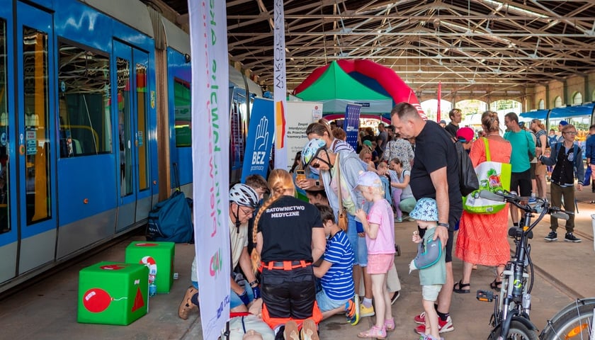 Piknik Bezpieczeństwa w zajezdni na Borku, 28 czerwca 2025, pokaz pierwszej pomocy w hali zajezdni, na zdjęciu uczestnicy wydarzenia oraz ratowniczka medyczna