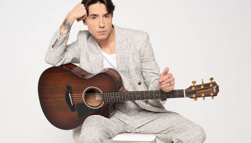 Dawid Kwiatkowski. Na zdjęciu młody mężczyzna z gitarą
