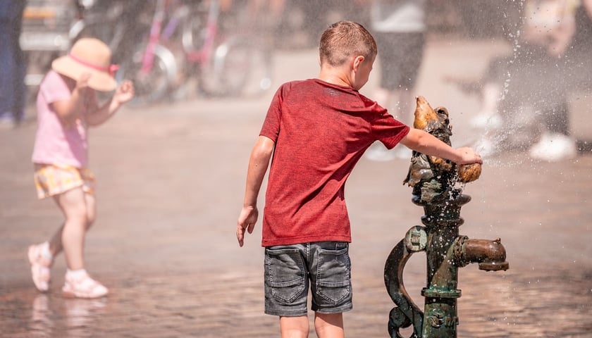 W upalną niedzielę każdy sposób na ochłodę jest dobry. Na zdjęciu chłopak chłodzi się przy zraszaczu na wrocławskim Rynku 
