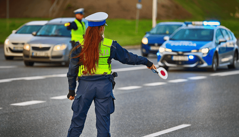 Kobieta w policyjnym mundurze na drodze, w tle samochody, zdjęcie ilustracyjne