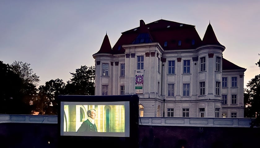 Pokazy filmowe w OPT Zamek na osiedlu Leśnica, na zdjęciu zabytkowy budynek, ustawiony przed nim ogromny ekran
