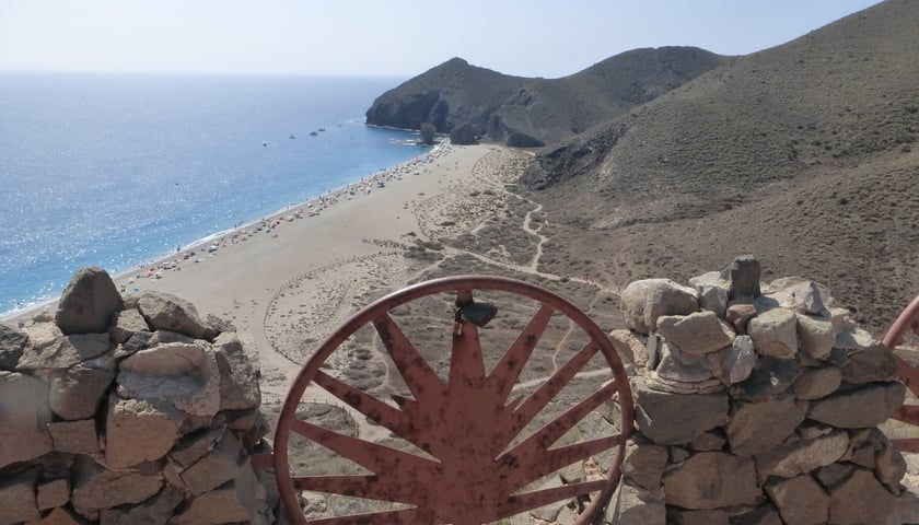 Widok na Playa de Los Muertos z punktu widokowego. W dole długa na kilometr plaża, a na niej odpoczywający ludzie.  Plaża wygrała wiele plebiscytów na najpiękniejszą w Hiszpanii. Warto się tam wybrać z Malagi.