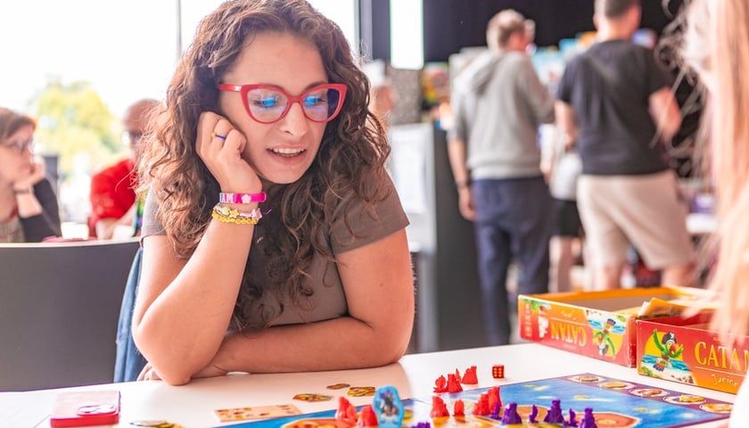 Kobieta w okularach przy stoliku z grą planszową