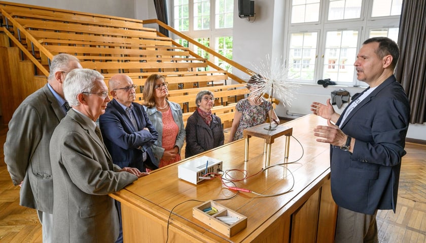 Sala wykładowa, zajęcia na Politechnice Trzeciego Wieku. Wykładowca mówi do grupy seniorów