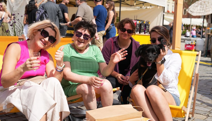 Festiwal Piwa, Wina i Sera FETA 2025, 2 sierpnia 2025 roku, Wrocław. Na zdjęciu 4 uśmiechnięte, siedzące na leżakach osoby oraz pies