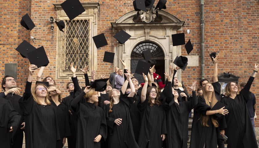 Grupa studentów i studentek podrzucających czapki. Zdjęcie archiwalne, wykonane w 2023 roku. 