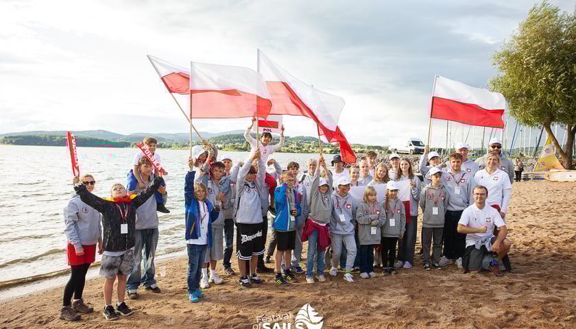 Reprezentacja Polski na Mistrzostwa Świata klasy Cadet 2025 w Czechach stoi nad brzegiem jeziora z polskimi flagami
