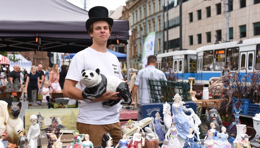 Giełda Staroci w okolicach Rynku, przy Kościele św. Marii Magdaleny na skwerze przy rogu ulic Szewskiej i Wita Stwosza- 8-10 sierpnia. Mężczyzna w kapeluszu trzyma ceramicznego misia przy swoim stoisku.