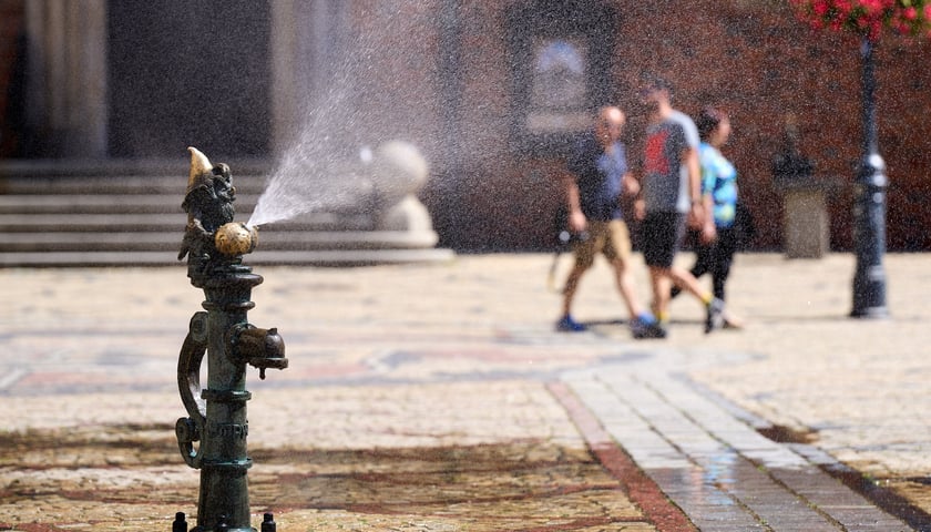 Kurtyna wodna na rynku, w tle trzy osoby, w kółku z prawej termometr