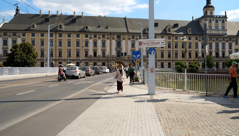 Widok na most Uniwersytecki i gmach główny UWr, na moście piesi i auto (19 sierpnia 2025)