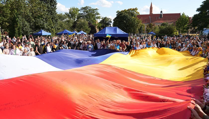 Flagi Polska i Ukraińska trzymane przez tłum stojących w koło ludzi