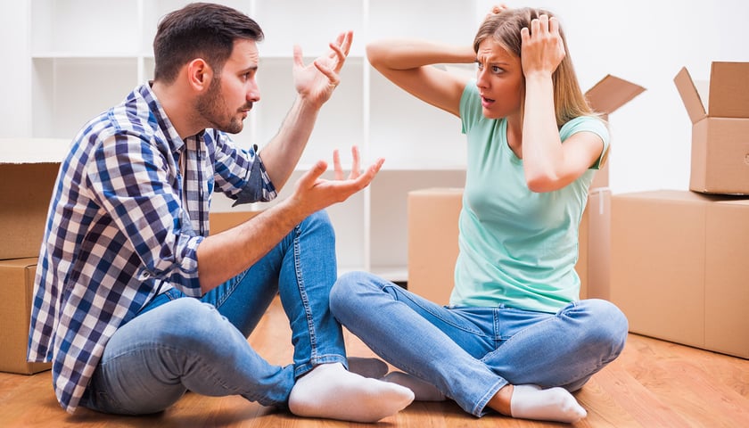 Kobieta i mężczyzna siedzą na podłodze w pokoju i gestykulują, zdjęcie ilustracyjne