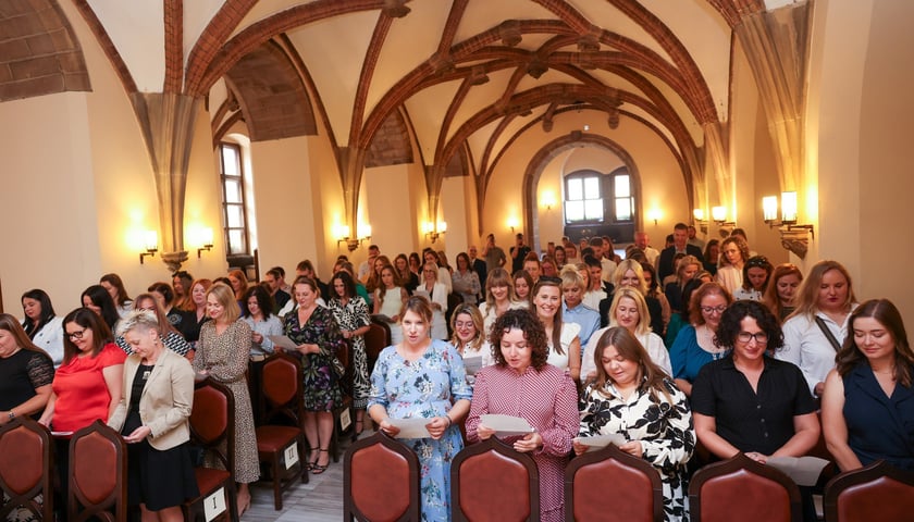 Nauczyciele, którzy odebrali dziś awans - osoby z kartkami odczytujące przysięgę