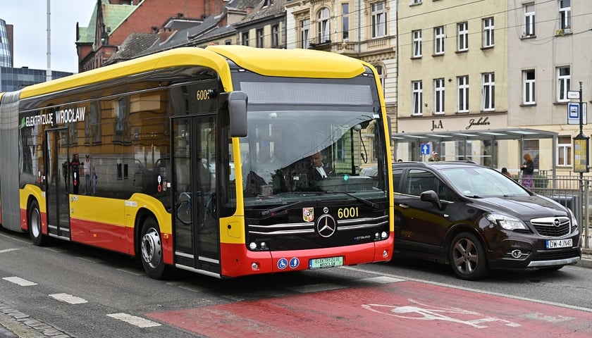 Żółto-czerwony autobus MPK Wrocław z tablicą rejestracyjną, która zamiast białego ma zielone tło - pierwszy autobus elektryczny na ulicach Wrocławia w roku 2023