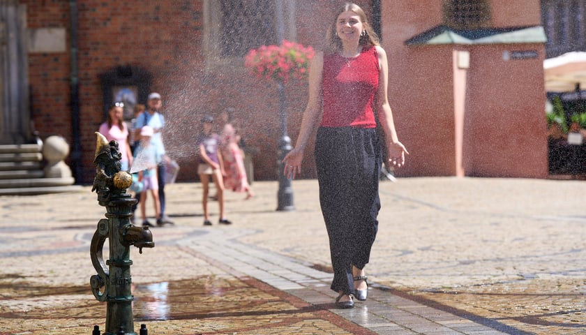 Kobieta przechodzi przez kurtynę wodną na wrocławskim rynku