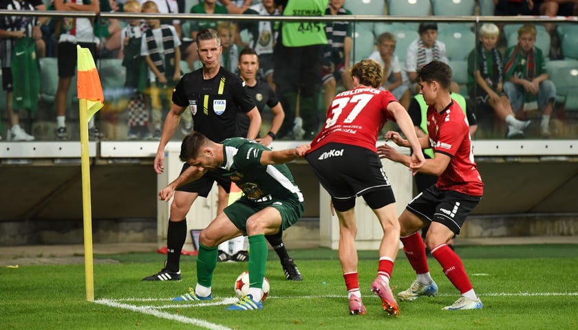 Mecz Śląska Wrocław z GKS Tychy. Na zdjęciu trzech zawodników walczy o piłkę w narożniku boiska