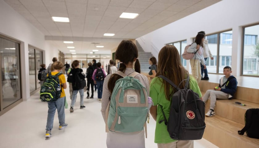 Uczniowie z plecakami na szkolnym korytarzu, zdjęcie ilustracyjne