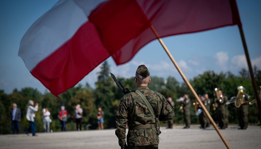 Żołnierz pod łopoczącą flagą Polski