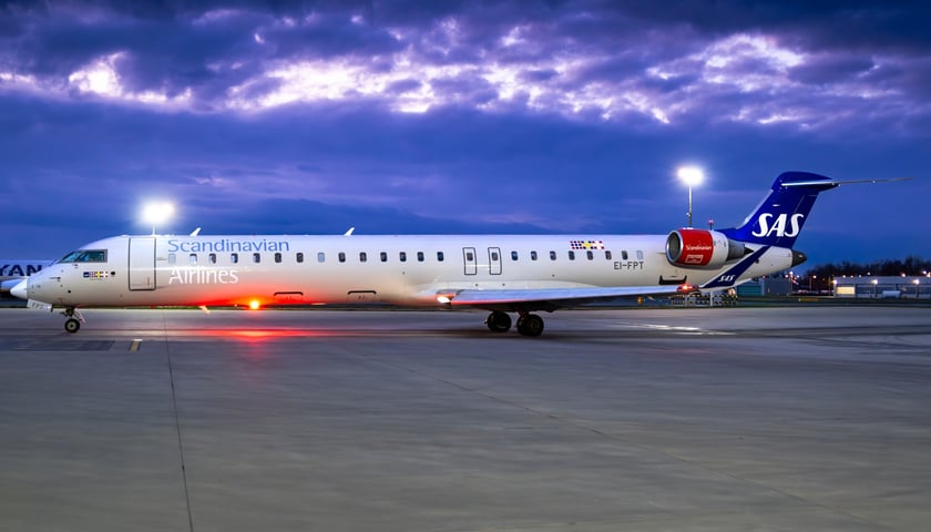 Samolot na płycie lotniska na tle pochmurnego nieba wieczorem. Maszyna linii SAS