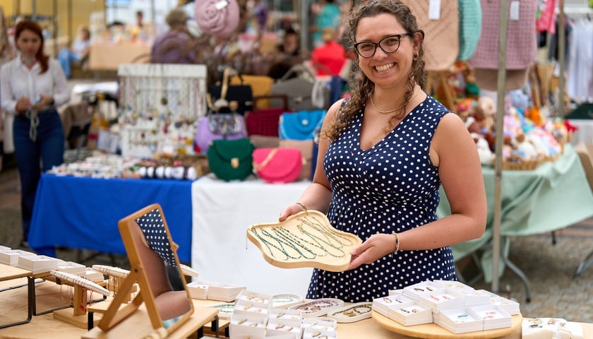 Artishop. Targi rzeczy niepospolitych na  ul. Szewskiej - weekend 5-7 września. Uśmiechnięta kobieta prezentuje swoje stoisko