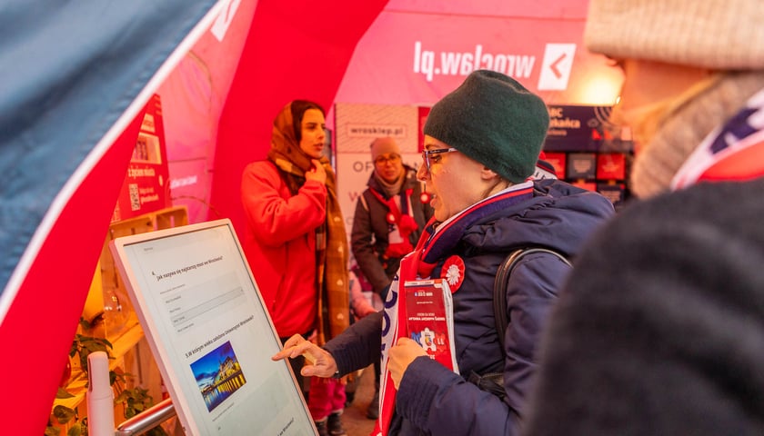 Uczestnicy WrocWalk 2024. Na zdjęciu kobieta rozwiązuje quiz