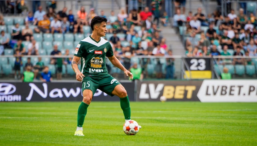 Piłkarz w zielono-białym stroju przyjmuje piłkę na boisku. Jorge Yriarte z drużyny WKS Śląsk Wrocław.