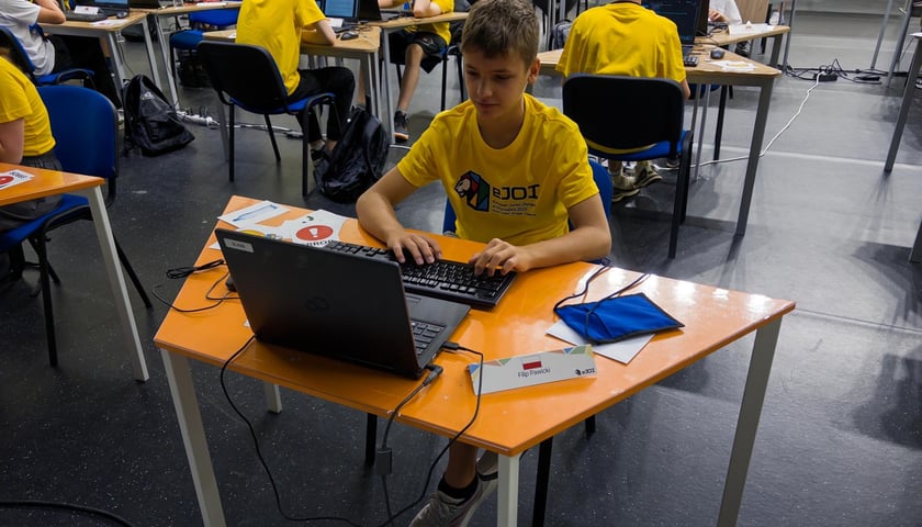 Filip Pawicki przy stoliku rozwiązujący zadania w trakcie olimpiady