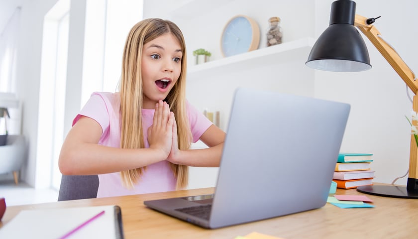 Na zdjęciu dziewczyna siedzi przed monitorem komputera. Zdjęcie ilustracyjne