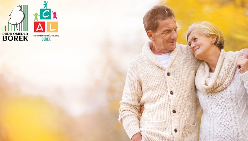 Mężczyzna w średnim wieku z kobietą w podobnych latach - oboje w białych ubraniach - uśmiechają się do siebie