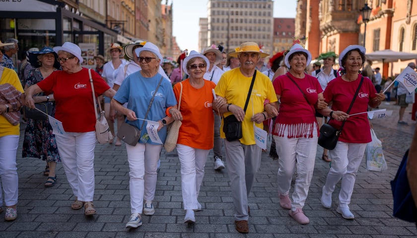 Uczestnicy Dni Seniora na wrocławskim Rynku - wszyscy w białym spodniach, kolorowych koszulkach i kapeluszach 