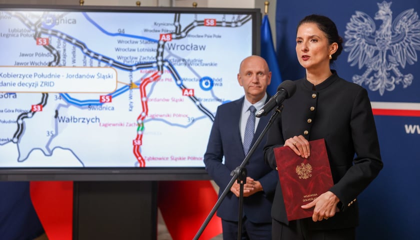Anna Żabska, wojewoda dolnośląska. Na zdjęciu kobieta podczas spotkania z dziennikarzami, w tyle szkic dróg